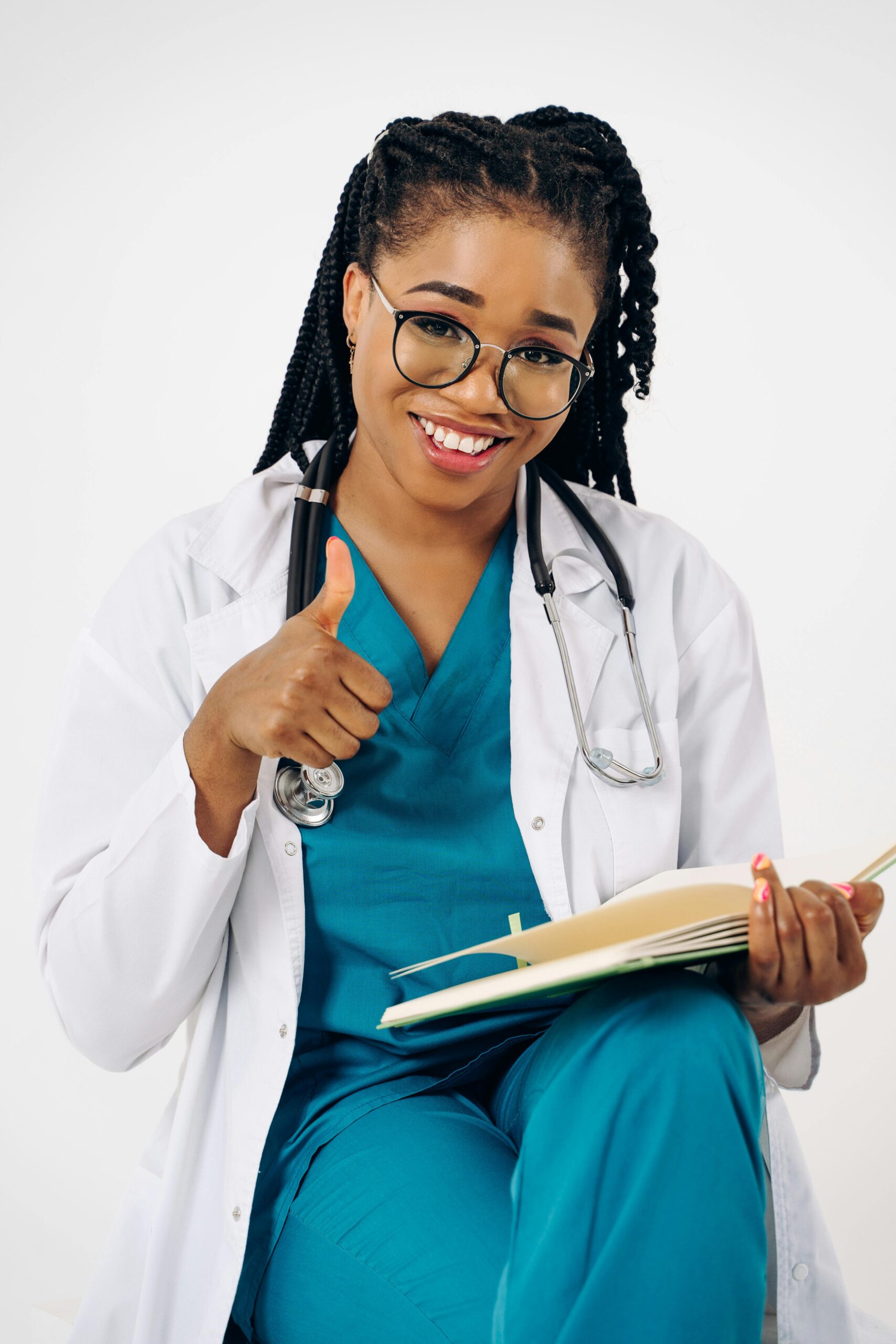 Confident female doctor in scrubs smiling and giving a thumbs up, representing healthcare professionalism.